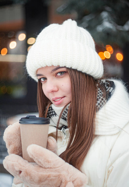 Smiling young woman drinking coffee in snowy forest. Winter vacation. - Fotó, kép