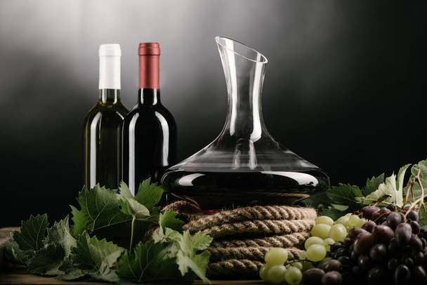 Wine decanter, bottle, glass of red wine and grapes close up - Fotó, kép
