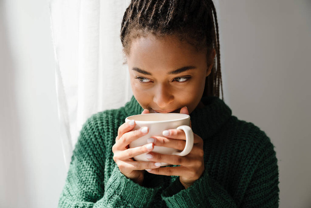 Молода чорна жінка з кісками п'є чай вдома
 - Фото, зображення