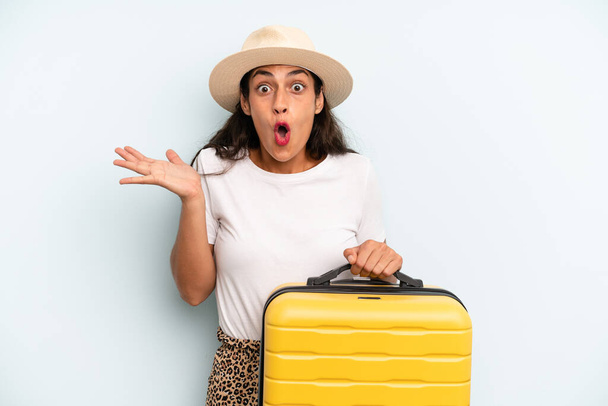 hispanic woman looking surprised and shocked, with jaw dropped holding an object. summer concept - Foto, Bild