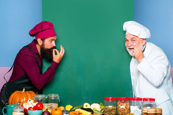 Two smiling male chefs, cooks or bakers with menu blank board. Perfect hand sign - Foto, imagen