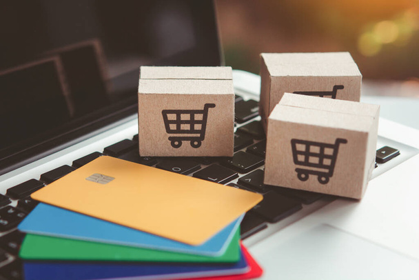 Online einkaufen. Kreditkarten- und Kartonschachtel mit einem Warenkorb-Logo auf der Laptop-Tastatur. Shopping-Service im Internet. bietet Lieferung nach Hause - Foto, Bild