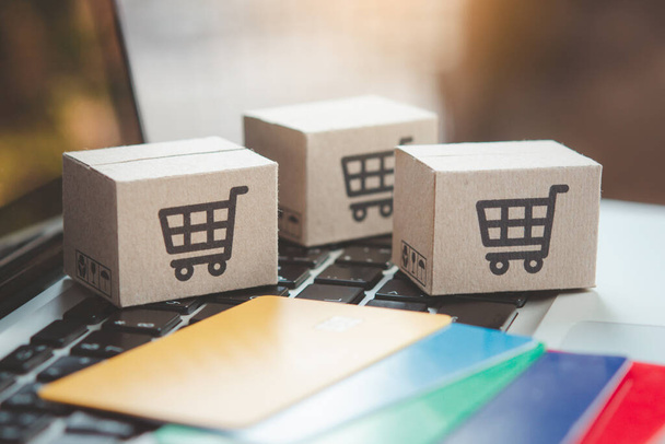 Shopping online. Credit card and cardboard box with a shopping cart logo on laptop keyboard. Shopping service on The online web. offers home delivery - Fotoğraf, Görsel