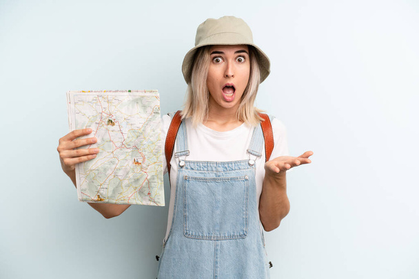 blonde woman amazed, shocked and astonished with an unbelievable surprise. tourist and map concept - Fotó, kép