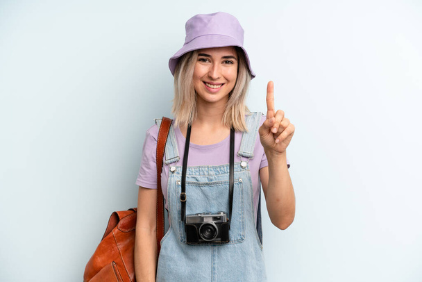 blonde woman smiling and looking friendly, showing number one. summer tourist concept - Foto, afbeelding