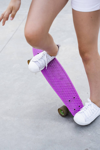 Child girl ride on penny board close up. Sports equipment for kids. Teenager with penny board on skate park playground - Photo, image