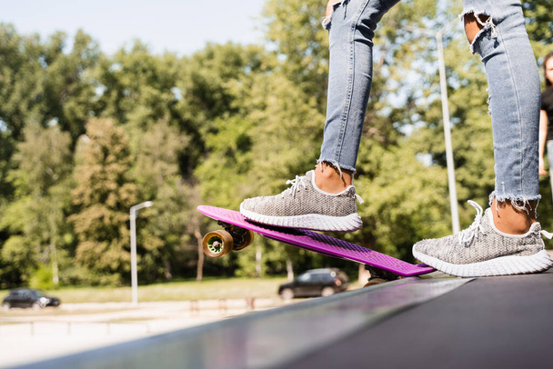 Menina adolescente com placa de centavo pronto para descer no parque de skate. Equipamento desportivo. Estilo de vida extremo - Foto, Imagem