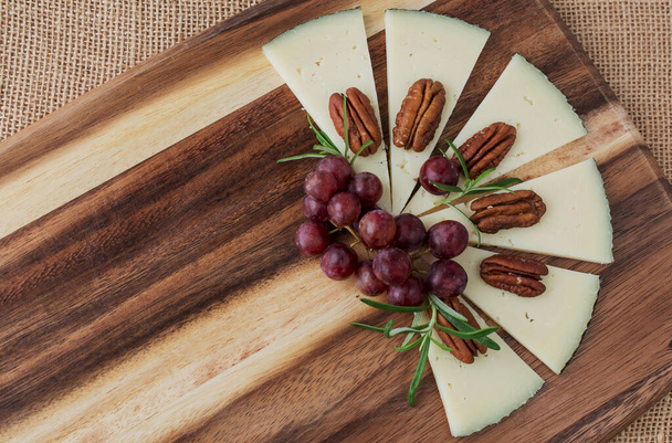Assorted cheeses with grapes, nuts, Goat cheese. wooden board. - Photo, Image