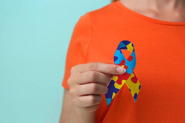 Welttag des Autismus-Bewusstseins. Frau mit buntem Puzzle-Band auf hellblauem Hintergrund, Nahaufnahme - Foto, Bild