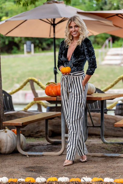 A gorgeous Blonde model poses in a pumpkin field during the halloween holidays - 写真・画像