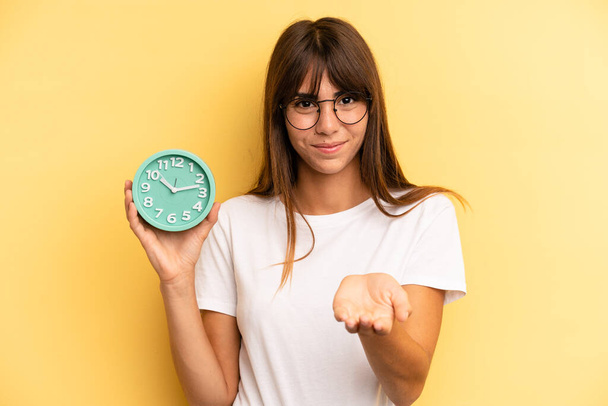 hispanic woman smiling happily with friendly and  offering and showing a concept. alarm clock concept - Foto, Imagem