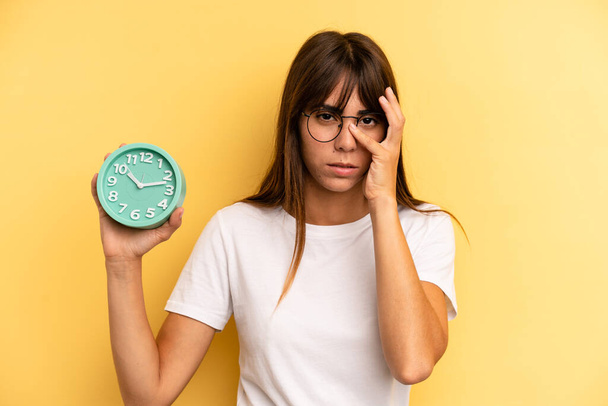 hispanic woman feeling bored, frustrated and sleepy after a tiresome. alarm clock concept - Foto, Imagem
