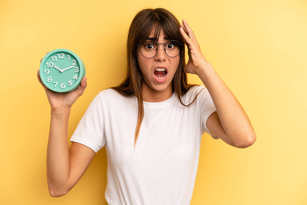 hispanic woman screaming with hands up in the air. alarm clock concept - Fotoğraf, Görsel