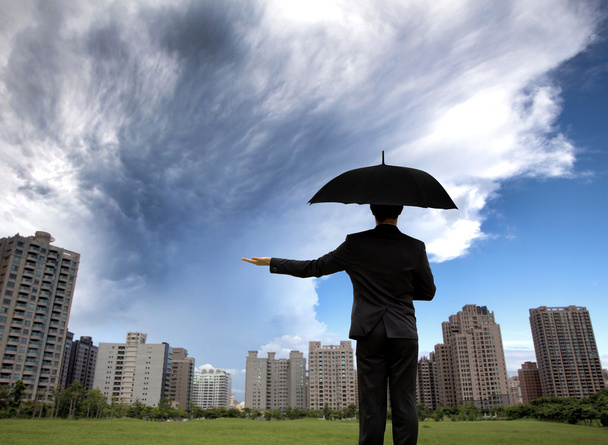 επιχειρηματία στο σκοτεινό σουίτες με ομπρέλα και βλέποντας καταιγίδα - Φωτογραφία, εικόνα