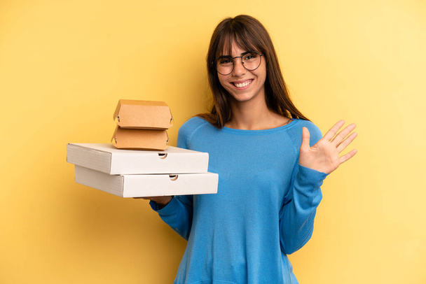 pretty woman smiling and looking friendly, showing number five. take away fast food concept - Fotoğraf, Görsel