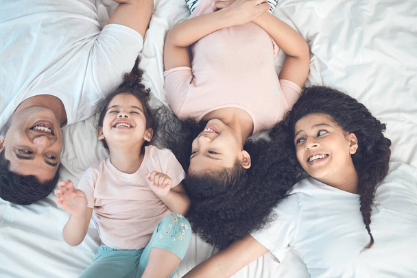 Shot of a beautiful young family talking and bonding in bed together. - Foto, Bild