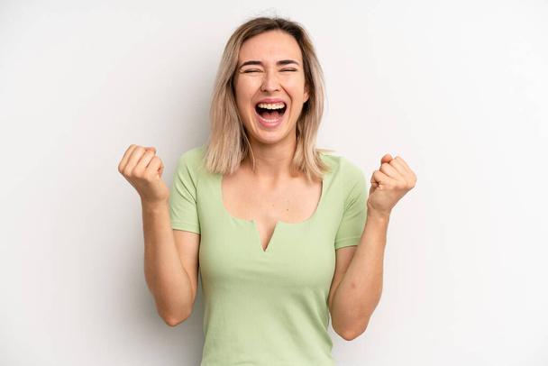 young adult blonde woman looking extremely happy and surprised, celebrating success, shouting and jumping - Photo, image