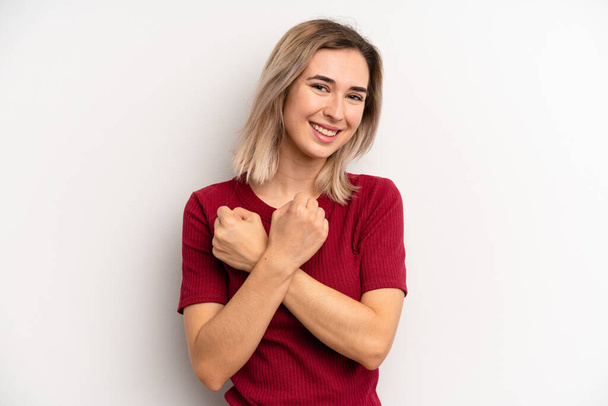 young adult blonde woman smiling cheerfully and celebrating, with fists clenched and arms crossed, feeling happy and positive - Photo, Image