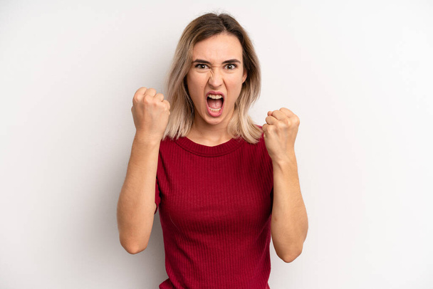 young adult blonde woman shouting aggressively with an angry expression or with fists clenched celebrating success - Photo, image