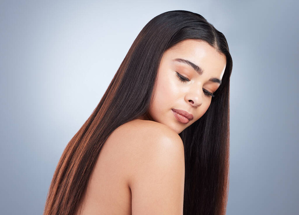 Beautiful young woman with shiny brown and straight long hair. Young girl looking down at her shoulder and showing off healthy-looking hair. - Foto, Imagen
