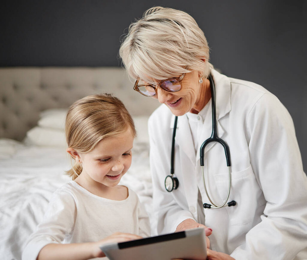 Shot of a girl and a doctor using a tablet at home. - Foto, Bild