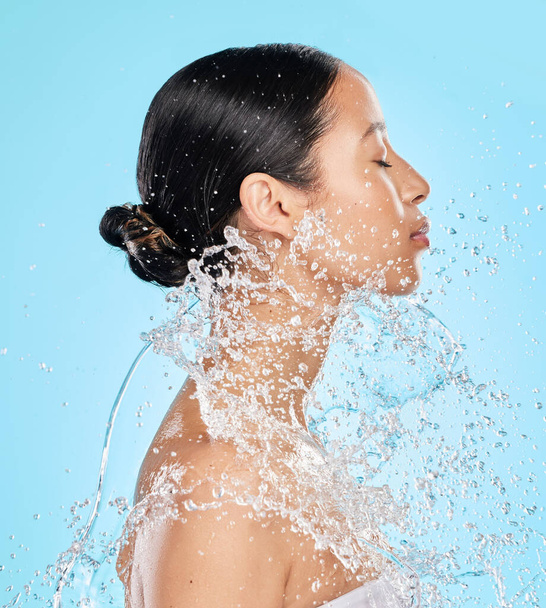 Shot of a beautiful young woman being splashed with water against a blue background. - Foto, immagini