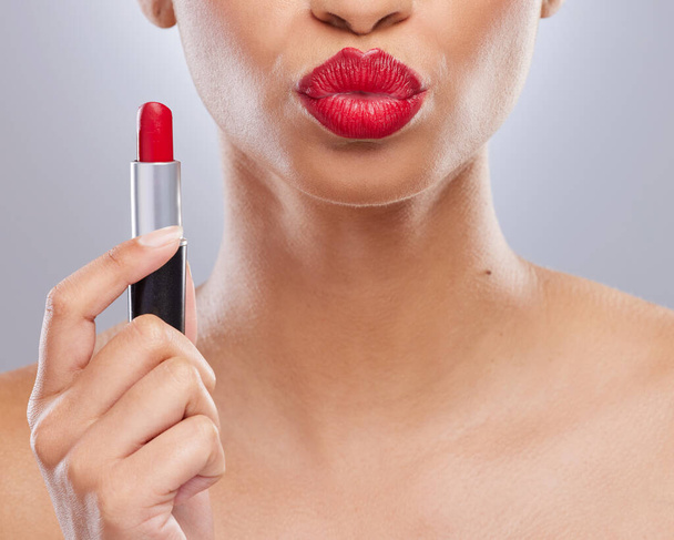Fotografía recortada de una mujer irreconocible sosteniendo lápiz labial rojo y haciendo pucheros en el estudio. - Foto, imagen