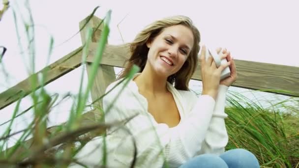 Κορίτσι στην παραλία πίνοντας καφέ - Πλάνα, βίντεο