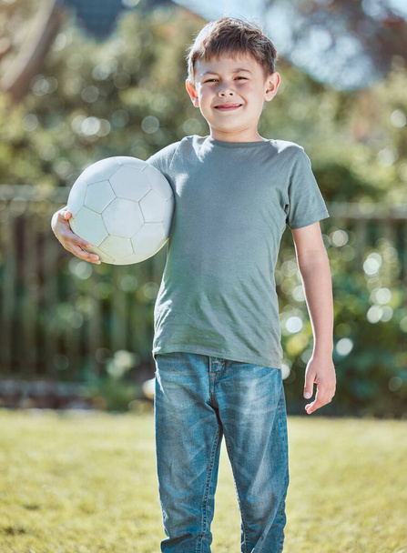 Shot of an adorable little boy holding a soccer ball outside. - Fotó, kép