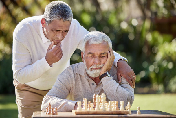 Shot of two senior men playing a game of chess outside. - Фото, изображение