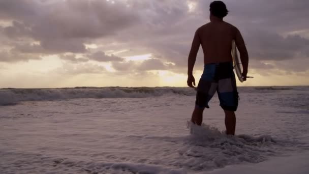 Серфер на пляже наблюдает за волнами
 - Кадры, видео