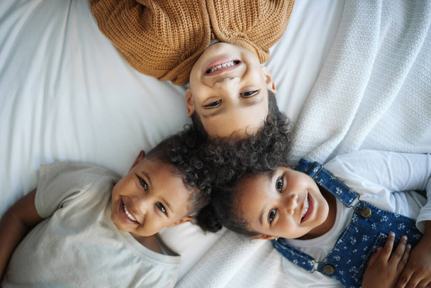 Portrait of three siblings bonding in bed at home. - Foto, imagen