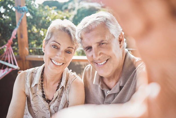 Shot of a mature couple taking a selfie while sitting outside. - 写真・画像