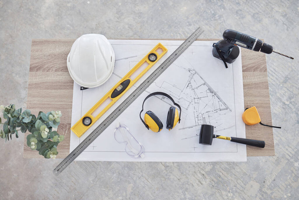 High angle shot of building plans and equipment on a table in an empty living room during the day. - 写真・画像