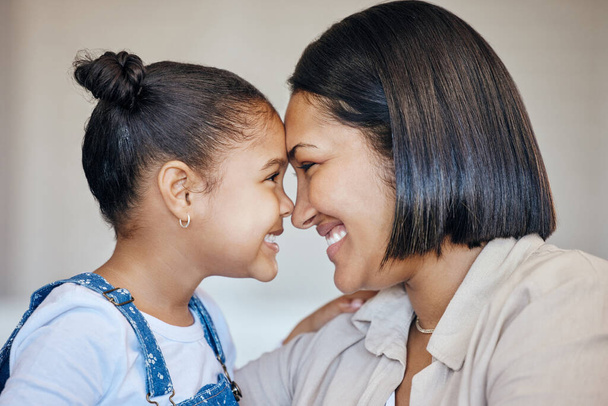 Adorable little girl and mom touching foreheads. Closeup of happy mother and daughter looking into each others eyes. Mixed race family expressing love, enjoying tender moment together at home. - Foto, Imagem