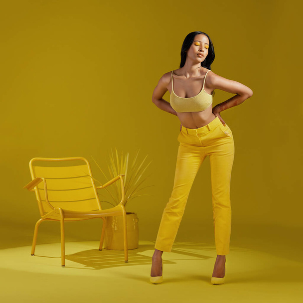 Studio shot of a young woman dressed in stylish yellow clothes against a yellow background. - Photo, Image
