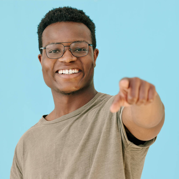 Shot of a man pointing at the camera while posing against a blue background. - Foto, Imagen