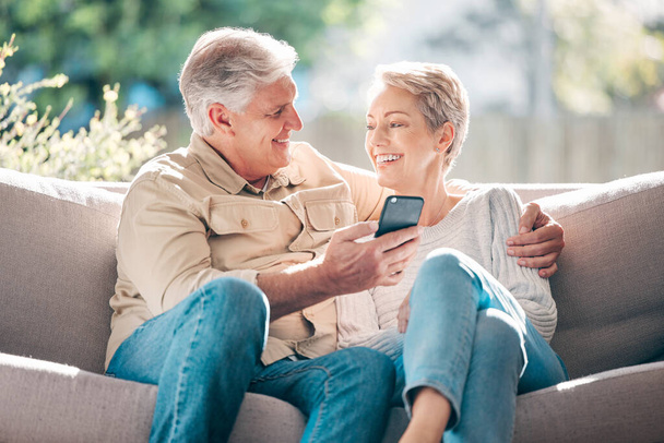 Shot of a happy senior couple using a smartphone on the sofa at home. - Foto, imagen