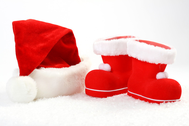 Sombrero y botas de Santa Claus sobre nieve delante de fondo blanco - horizontal
 - Foto, Imagen