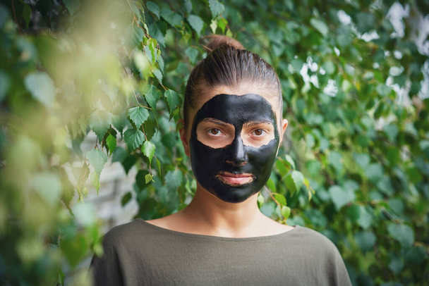 Mujer joven en la naturaleza con máscara negra en la cara. Foto de alta calidad - Foto, Imagen