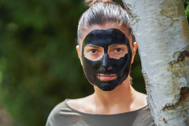 Młoda kobieta w naturze z czarną maską na twarzy. Wysokiej jakości zdjęcie - Zdjęcie, obraz