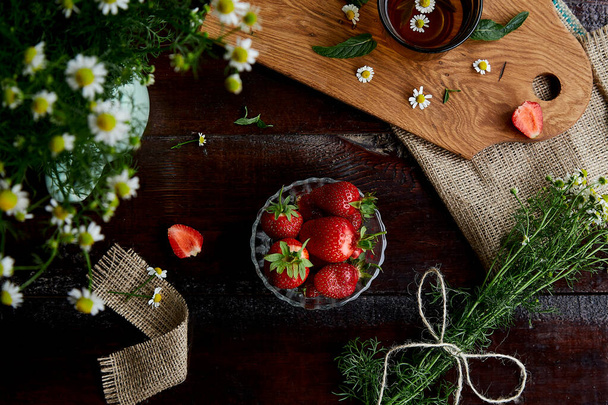Natural organic breakfast. Fresh strawberries, summer chamomile flowers, herbal tea and mint on wooden table. Atmospheric summer lifestyle. Beautiful food. Connecting ith nature. Copy space.  - 写真・画像