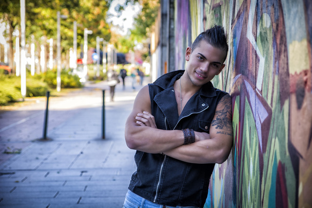 Handsome young man against colorful graffiti wall - Foto, afbeelding