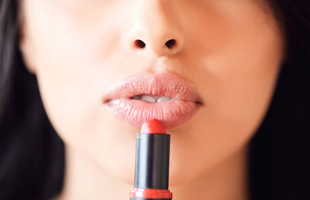 Shot of an unrecognizable woman applying lipstick at home. - 写真・画像