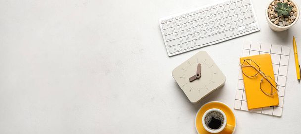 Alarm clock, computer keyboard, notebooks, eyeglasses and cup of coffee on light background with space for text - Foto, immagini