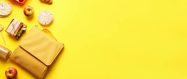 Child's bag with different food on yellow background with space for text - Foto, Imagen