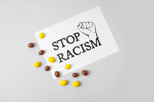 Doces e folha de papel com texto STOP RACISM em fundo cinza - Foto, Imagem