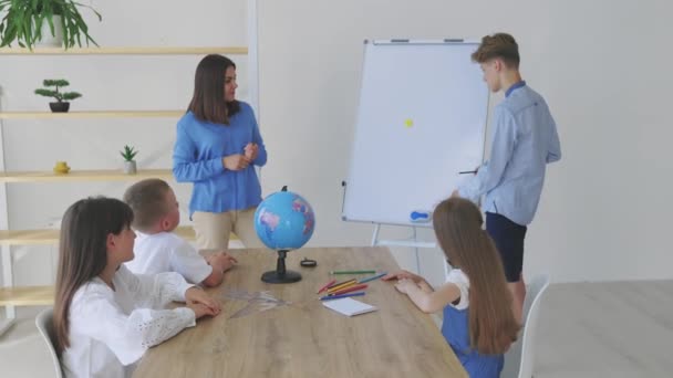 A teacher and students of different ages at a geography lesson. The student answers by standing near the board and tells the story - Filmati, video
