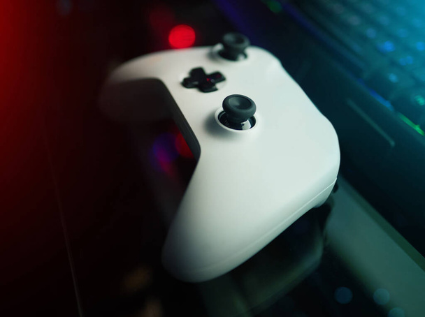 High angle shot of a console remote on a desk in a dark gaming room. - Foto, Bild