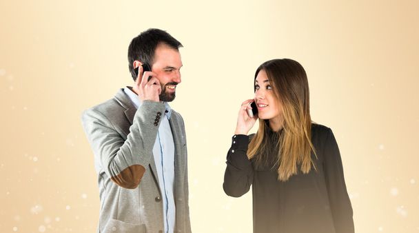 Couple talking to mobile over gloss background.  - Фото, зображення